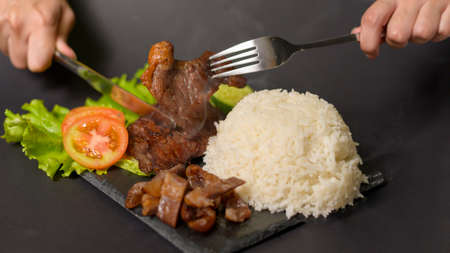 grilled beef with rice on plate over black background studio