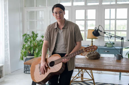 Portrait of a musician man holding guitar in home Studioの写真素材
