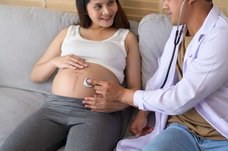 A doctor holding stethoscope is examining a pregnant woman in the hospital , healthcare and pregnancy care conceptの写真素材
