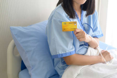 A young patient woman is holding credit card , admitting in hospital , Health care  conceptの写真素材