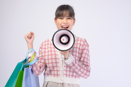 An attractive shopper woman holding shopping bags over white backgroundの写真素材