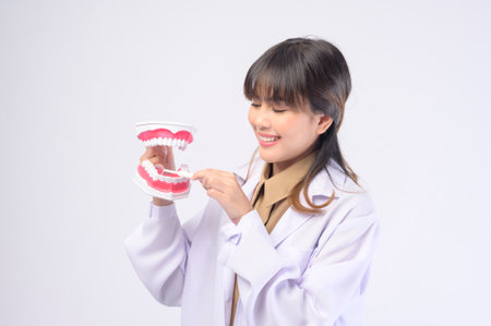 A young female dentist smiling over white background studio