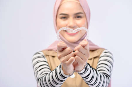 A young muslim woman holding invisalign braces in studio, dental healthcare and Orthodontic concept..の写真素材