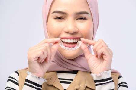 A young muslim woman holding invisalign braces in studio, dental healthcare and Orthodontic...