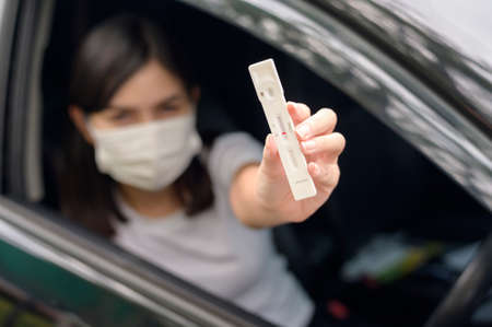 A woman holding atk in car, do a self-collection test