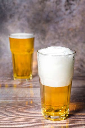 Cold craft  light Beer is pouring from bottle on wooden Tableの写真素材
