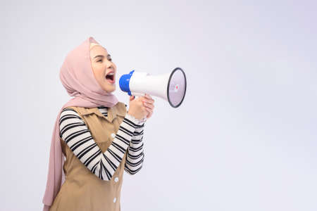 Happy muslim woman is announcing with megaphone on white backgroundの写真素材