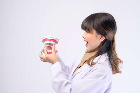 A young female dentist smiling over white background studio