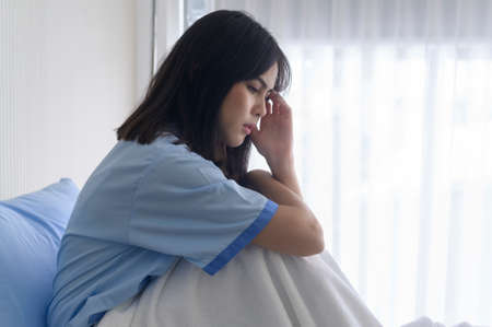 A despondent Asian woman patient. Following the doctor's declaration that the cancer was nearing the end of its course.の写真素材