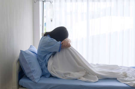 A despondent Asian woman patient. Following the doctor's declaration that the cancer was nearing the end of its course.の写真素材