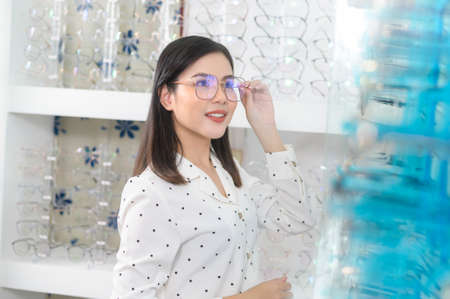A young female customer choosing glasses in optical center, Eyecare concept.の写真素材