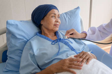 Cancer patient woman wearing head scarf after chemotherapy consulting and visiting doctor in...