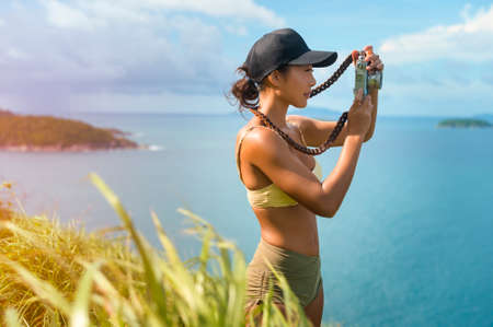 A Beautiful asian woman in sportswear taking photo on seaside mountain peak after trekking, Travel and ecotourism concept.の写真素材