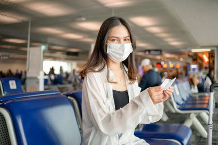 A traveller woman is wearing protective mask in International airport, travel under Covid-19 pandemic, safety travels, social distancing protocol, New normal travel concept .の写真素材