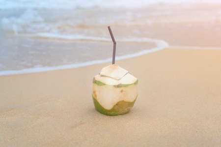 A Fresh coconut with drinking straw on the beach, travel and holidays concept.の写真素材
