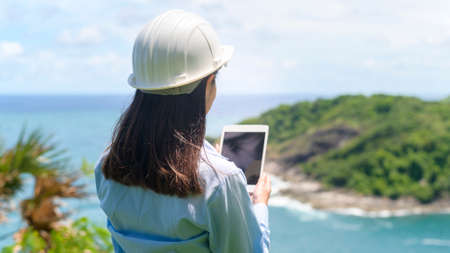A Female engineer working on the seaside wearing a protective helmetの写真素材