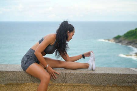 A Beautiful fit woman in sportswear exercising on seaside mountain peak, Health and Travel concept.