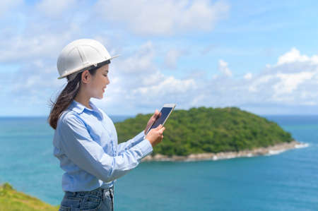 A Female engineer working on the seaside wearing a protective helmetの写真素材
