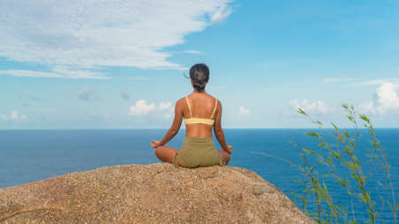 A Beautiful asian woman in sportswear doing yoga on seaside mountain peak after trekking, Travel and meditation concept.の写真素材