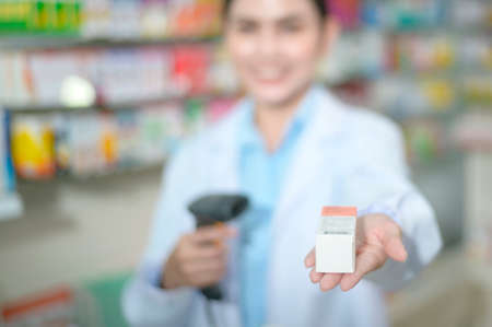 A Female pharmacist scanning barcode on a medicine box in a modern pharmacy drugstore.の写真素材