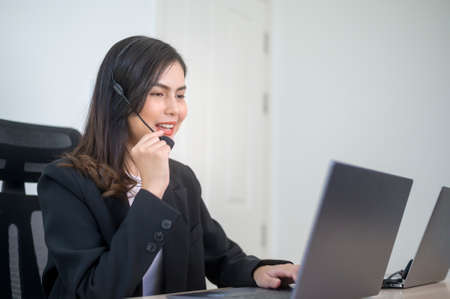 A Female call center agent with headset consulting clients online, customer service and customer...