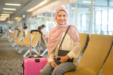 A Young female muslim traveler carrying suitcases at the International airport, travel, holidays and journey concept.の写真素材