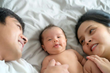 Smiling young mother and father with a new born baby, family and love conceptの写真素材