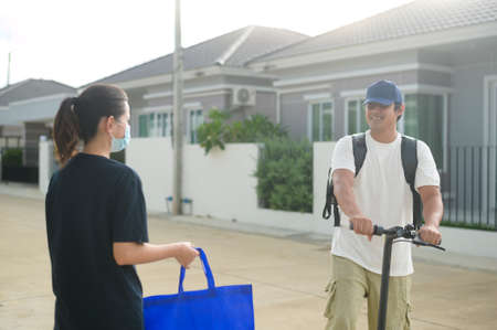 A Smiling delivery man with thermal backpack riding on an electric scooter, deliver online concept