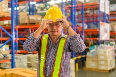 A Portrait of senior asian male worker wearing helmet in modern warehouse storage of retail shop
