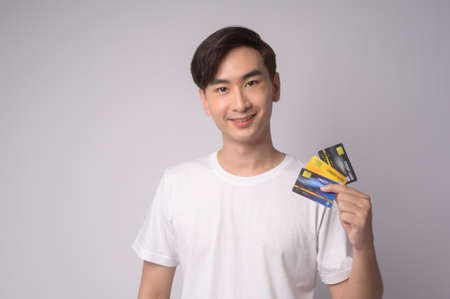 A Young asian man holding credit card over white background studio, shopping and finance concept.の写真素材