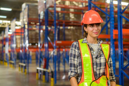 A Portrait of young mixed race female worker wearing helmet in modern warehouse storage of retail shopの写真素材