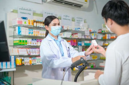 A Portrait of female pharmacist wearing face mask in a modern pharmacy drugstore.の写真素材
