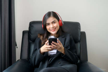 A Young relaxing business woman using smartphone and listening to music in modern office.の写真素材