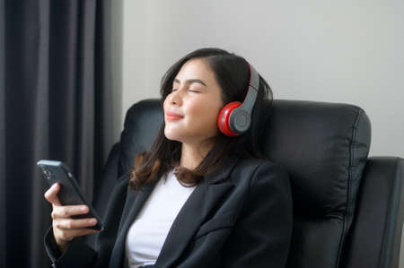 A Young relaxing business woman using smartphone and listening to music in modern office.の写真素材