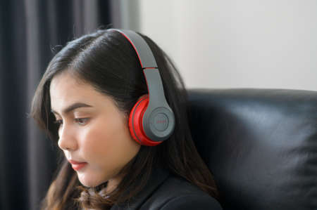 A Young relaxing business woman using smartphone and listening to music in modern office.の写真素材