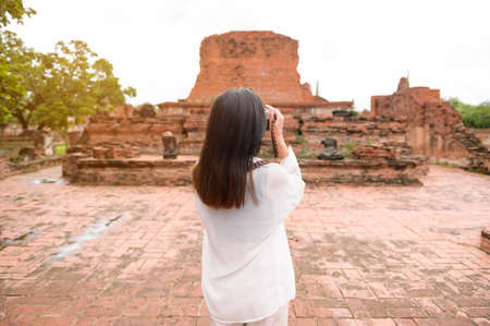 young beautiful woman traveling and taking photo at thai historical Park, Holidays and cultural tourism concept.の写真素材