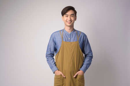 A Portrait of young asian man wearing apron over white background studio, cooking and entrepreneur conceptの写真素材