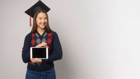A Young smiling woman holding graduation hat, education and university conceptの写真素材