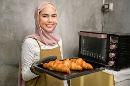 Young beautiful muslim woman is baking in her kitchen , bakery and coffee shop business