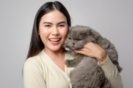A young woman is holding lovely cat , playing with cat in studio on white backgroundの写真素材