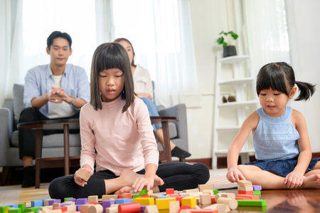 An Asian family with children playing and building tower of colorful wooden toy blocks in living room at home, Educational game.の写真素材
