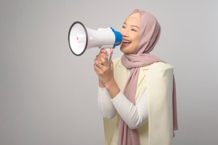 A Young beautiful woman holding megaphone over white background studio.