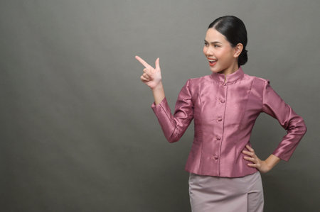 A young asian woman wearing Thai traditional cloth on gray backgroundの写真素材