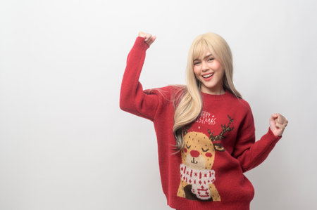 Portrait of happy Caucasian young woman in Christmas sweater over white backgroundの写真素材