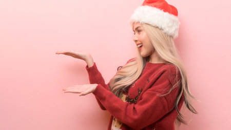 Portrait of happy Caucasian young woman in santa claus hat over pink backgroundの写真素材