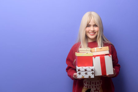 Portrait of happy Caucasian young woman  with gift box over purple backgroundの写真素材
