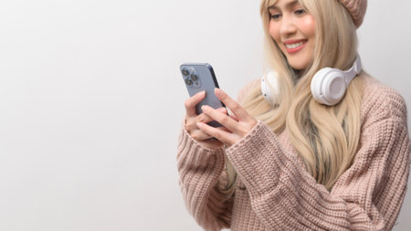 Portrait of Caucasian young woman wearing sweater holding smart phone   over white backgroundの写真素材