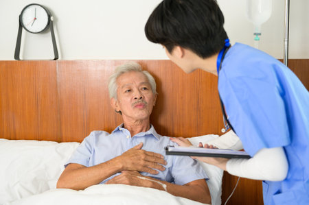 An Asian nurse taking care of an elderly man lying on patient bed at  senior healthcare center.の写真素材