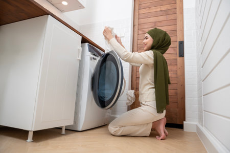 Happy young muslim woman wearing hijab doing laundry in home , healthy lifestyle conceptの写真素材