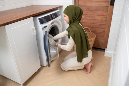 Happy young muslim woman wearing hijab doing laundry in home , healthy lifestyle conceptの写真素材